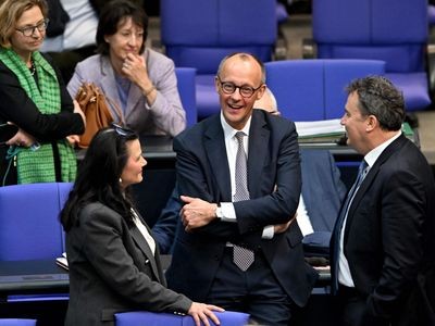 Friedrich Merz (2nd R), leader of Germany's conservative Christian Democratic Union (CDU) party, stands at the plenary hall during a session at the Bundestag (lower house of parliament) on March 18, 2025 in Berlin, Germany. German lawmakers will vote on a massive spending boost for defence and infrastructure proposed by chancellor-in-waiting Friedrich Merz amid concern over the United States' commitment to Europe's security. The hastily drawn plans represent a radical departure for a country traditionally reluctant to take on large amounts of debt or to spend heavily on the military, given the horrors of its Nazi past. (Photo by RALF HIRSCHBERGER / AFP)