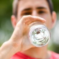 Manche Getränke versorgen den Körper nachhaltiger mit Flüssigkeit als reines Wasser – sogar über Stunden hinweg. Mann trinkt aus einer Wasserflasche