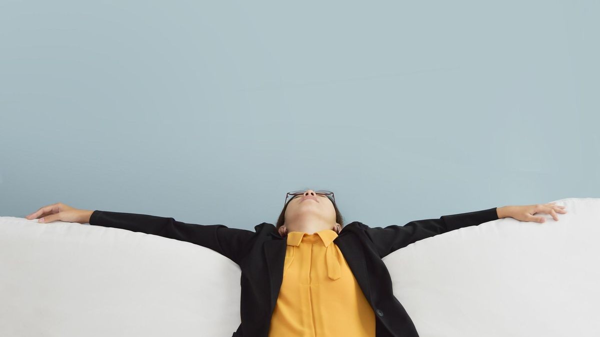 Exhausted, Tired, Lazy Asian Business woman in Yellow shirt and black suit sitting and sleepy on white sofa with blue wall and copy space. Stress from overtime working concept. ; Shutterstock ID 718434511; purchase_order: purchase_order; job: job; client: client; other: other
