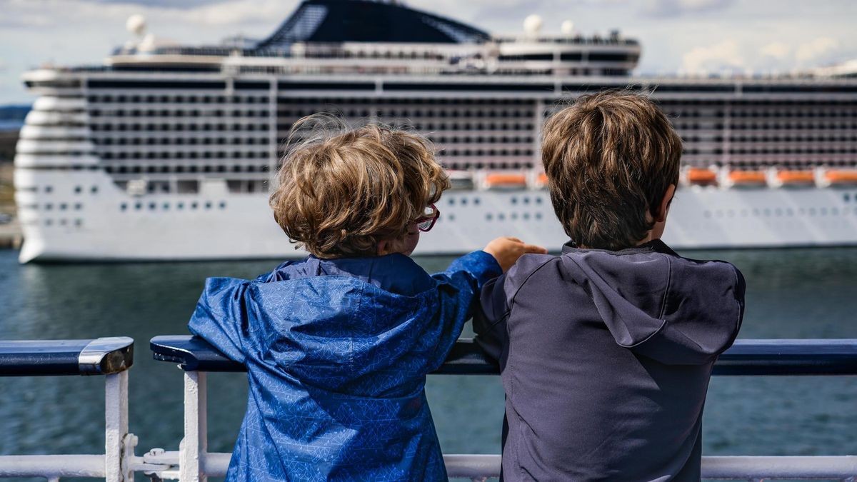 Two Boys On A Ferry Departing Copenhagen Harbor Point To A Large Cruise Ship