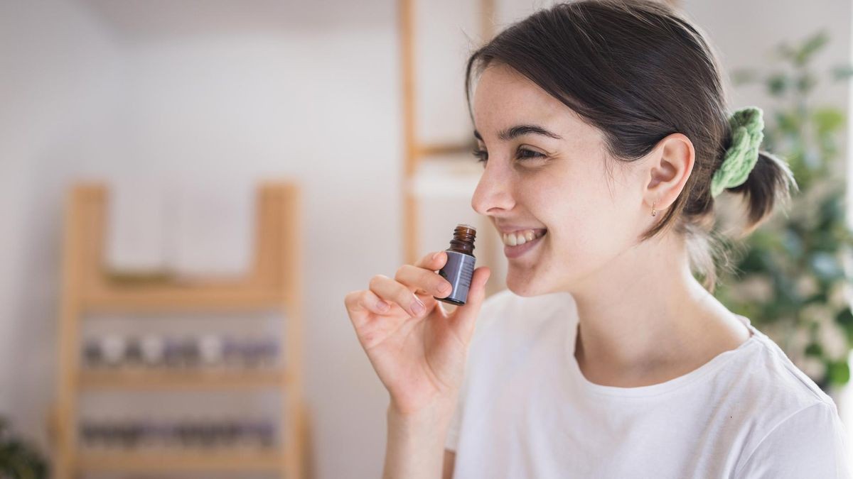 Smiling young woman smeling essential oil