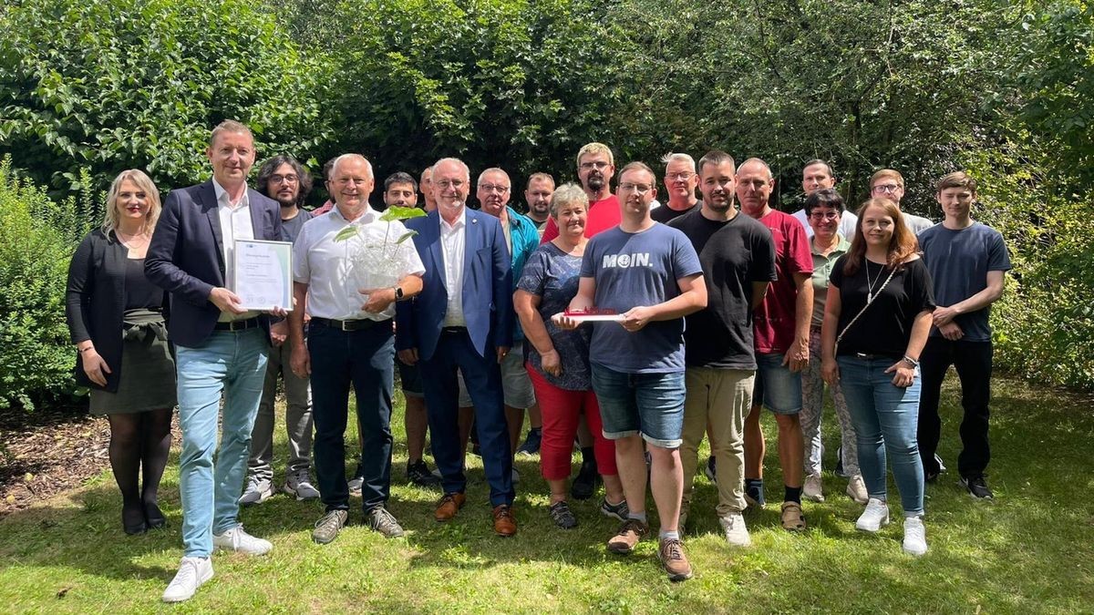 Stadtmarketing-Verantwortliche Lena Kob (von links), IHK-Geschäftsstellenleiter Markus Heyn, zweiter Syscon-Geschäftsführer Siegmar Egenolf, Bürgermeister Ralf Hauboldt, sowie Mitarbeitende des Unternehmens freuen sich über das 35-jährige Jubiläum.