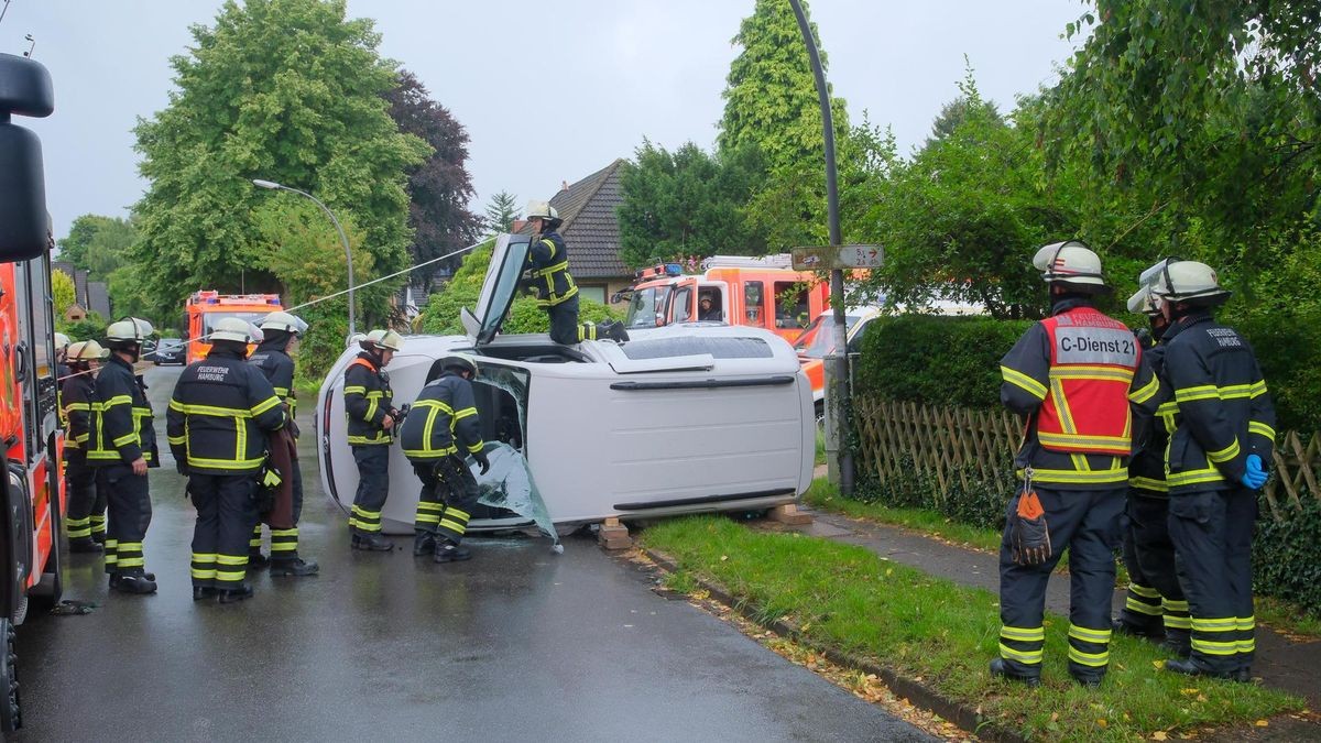 Rettungskräfte der Hamburger Feuerwehr sind in Rahlstedt an einem auf der Seite liegenden VW im Einsatz