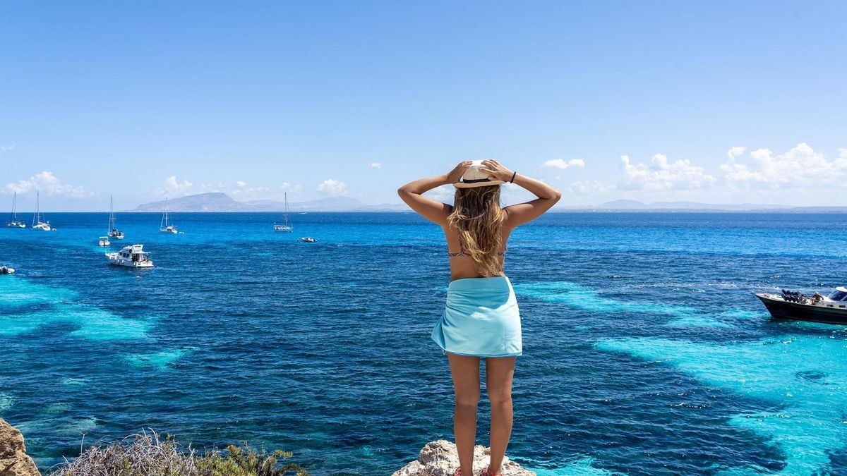 Woman on cliff looking at turquoise sea in Favignana, Sicily