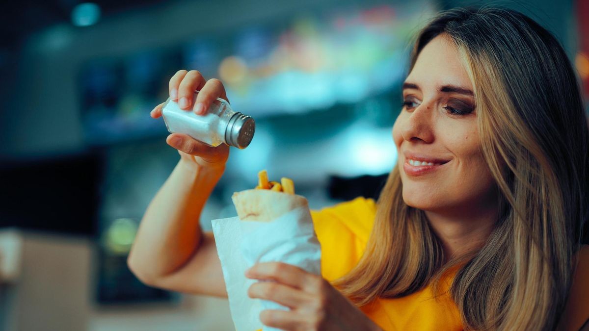 Woman Adding More Salt to a Restaurant Dish