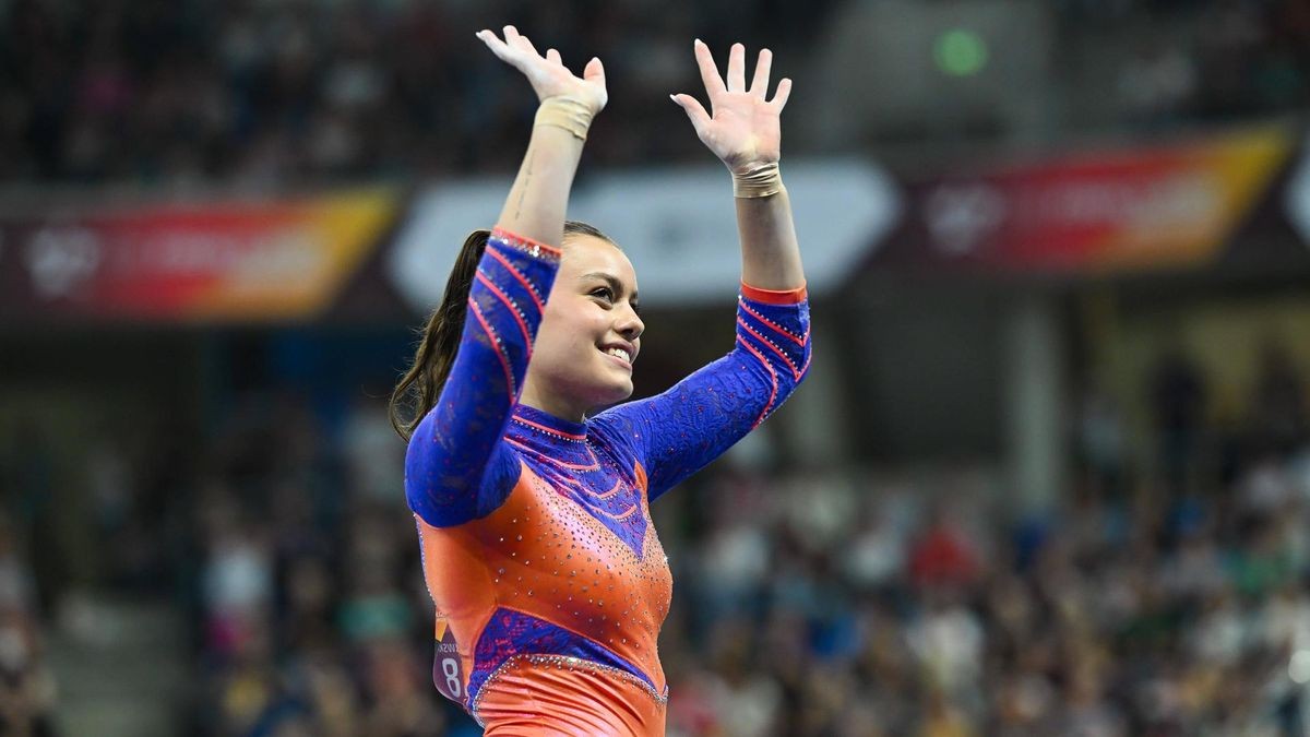 Die Turnerin Emma Malewski winkt lächelnd in Richtung der Zuschauer.