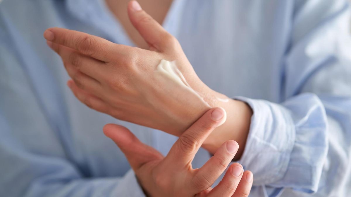 Hands in a blue shirt smear cream.