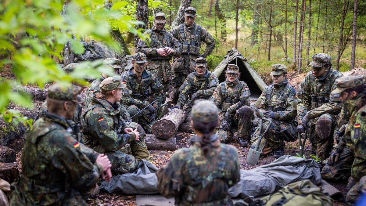 Mehrere Soldatinnen und Soldaten besprechen sich in einem Waldstück