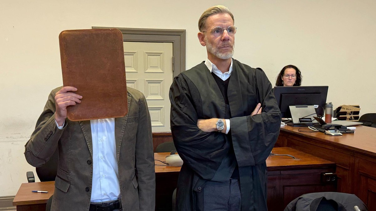 Der Angeklagte versteckt sich im Gericht hinter einem Aktendeckel, neben ihm  sein Anwalt Christian Simonis. 