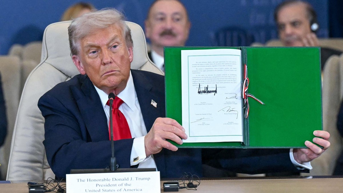 TOPSHOT - US President Donald Trump shows a signed document during a summit on Gaza in Sharm el-Sheikh on October 13, 2025. Trump landed in Egypt on October 13 for a summit on Gaza, following a lightning visit to Israel after a ceasefire he brokered entered into force. (Photo by SAUL LOEB / AFP)
