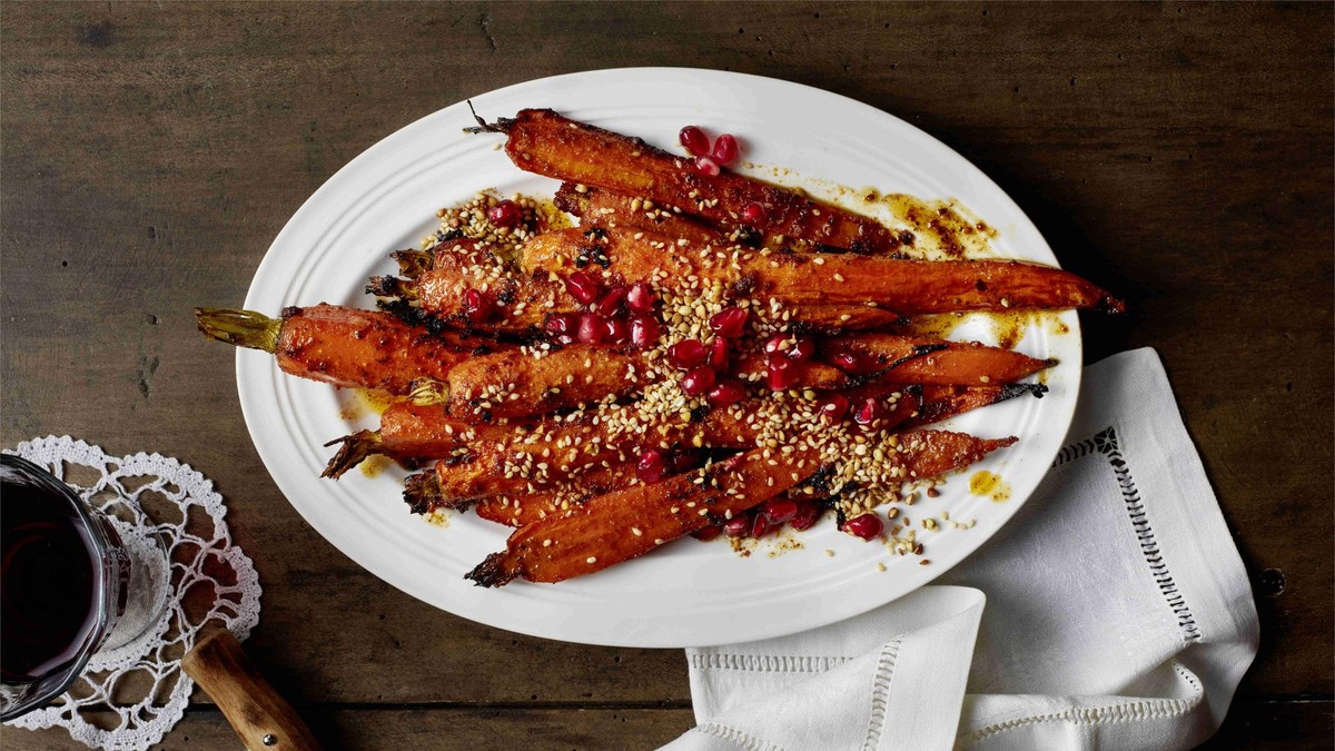 Teller mit gerösteten Möhrenscheiben, dazu Sesam, Buchweizen und Granatapfelkerne
