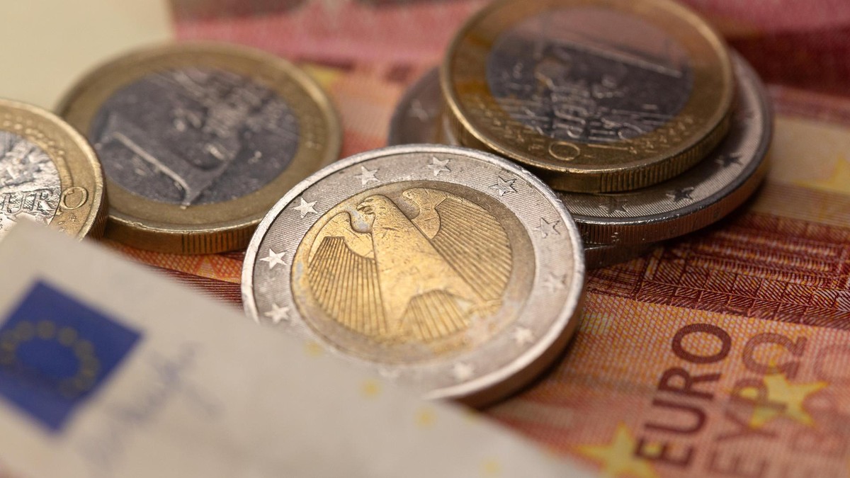 Geld: Euro-Münzen und Geldscheine liegen aufeinander